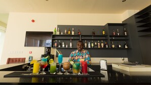 A bar area with a bartender, a variety of drinks, and shelves stocked with bottles. - Lodge by Eagles (Sekondi-Takoradi)