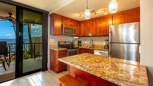 Una cocina con armarios de madera, encimeras de granito y electrodomésticos de acero inoxidable, con vistas al exterior.