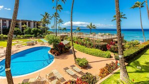 Un resort con piscina, sillones de descanso, palmeras y vistas al océano.