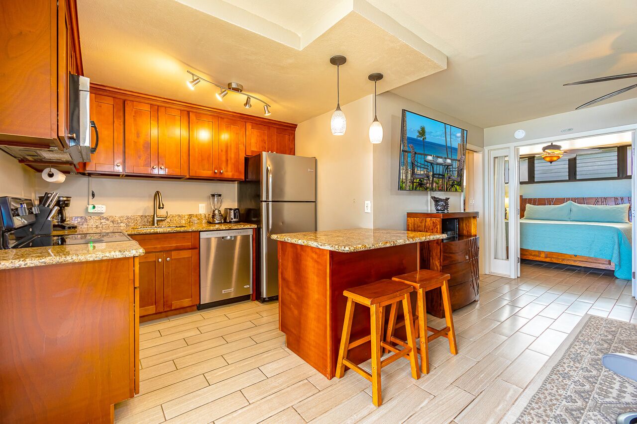 A modern kitchen with wooden cabinets, stainless steel appliances, and a bar area with stools.