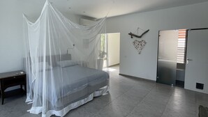 A bedroom with a bed under a white canopy, a bedside table, a wall-mounted light, and a heart-shaped decoration. - Luxury 4 bed Villa - Private Pool - Sleeps 8 (Jan Thiel)