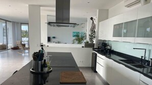 A modern kitchen with a central island, white cabinetry, and a large window. - Luxury 4 bed Villa - Private Pool - Sleeps 8 (Jan Thiel)
