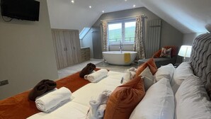 Una habitación de hotel con una cama grande, una bañera y una ventana con cortinas.