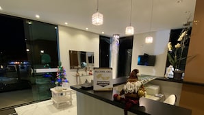 A modern reception area with a marble floor, a Christmas tree, and a sign for 'Álcool Gel'. - Pousada Vale do Chapéu (Capitólio)