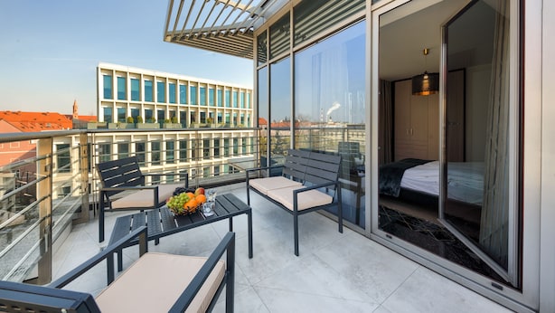 Een balkon met een tafel, stoelen en een bed.