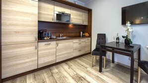 Een moderne keuken met houten kastjes, een ingebouwde magnetron, en een eethoek met tafel en stoelen.