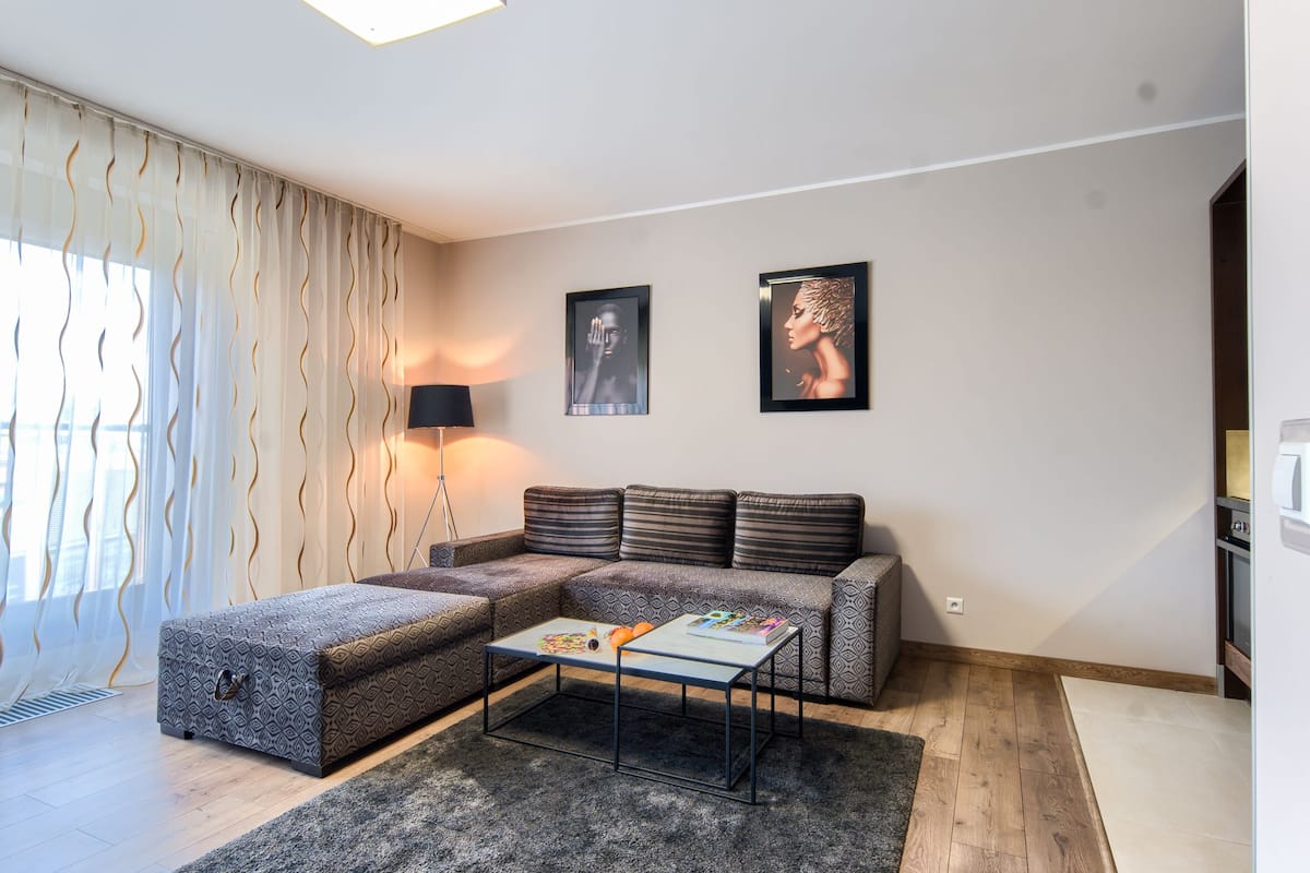 A modern living room with a sectional sofa, a coffee table, and two framed artworks on the wall.