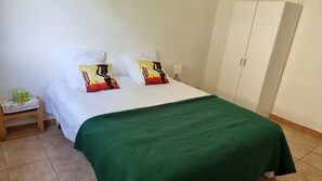 Cozy retreat with a bed dressed in crisp linens and a vibrant bedspread, accompanied by a nightstand and a wardrobe.