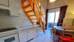 Eine Küche mit weißen Schränken, einer Holztreppe und einem Essbereich mit Tisch und Stühlen.