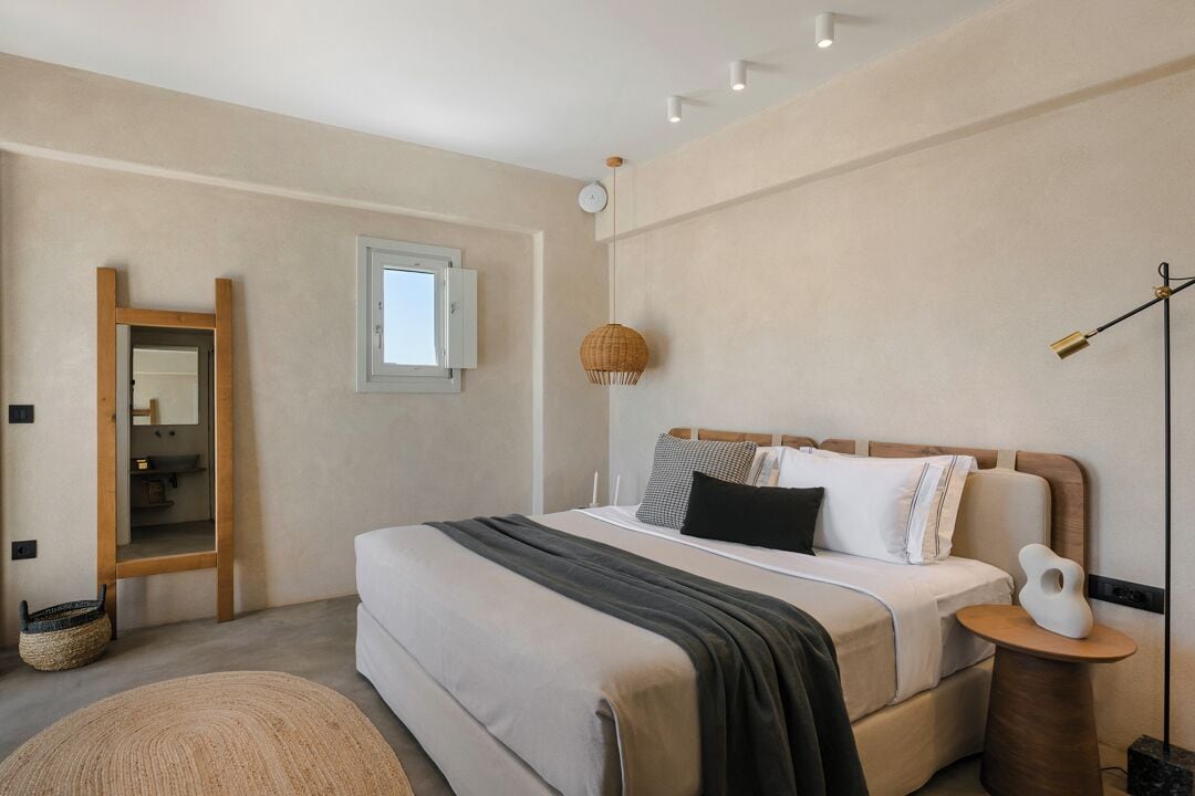 Quarto moderno com uma cama grande, mesa de cabeceira, luminária pendente e janela.