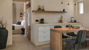 A modern kitchen with a wooden island, white cabinetry, and black chairs. - Ventus di Milo (Milos)