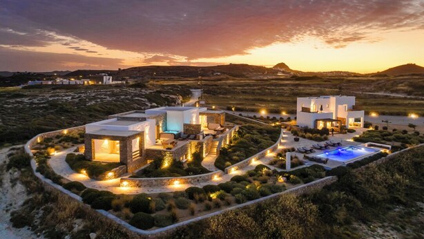 A modern resort with multiple buildings, a swimming pool, and a landscaped garden at dusk. - Ventus di Milo (Milos)