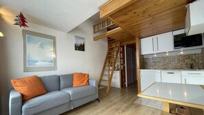 A compact living space with a sofa, a dining table, a kitchen area, and a loft bedroom accessible by a wooden ladder. - 10m from ski slopes, 13rd floor, view mountain, balcony, tv, 25m², Les Menuires (Les Menuires)