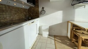 A kitchen with white cabinets, a tiled backsplash, a wooden dining table, and a small wooden stool. - 10m from ski slopes, 13rd floor, view mountain, balcony, tv, 25m², Les Menuires (Les Menuires)