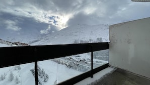A balcony with a metal railing overlooking a snowy landscape and a mountain. - 10m from ski slopes, 13rd floor, view mountain, balcony, tv, 25m², Les Menuires (Les Menuires)