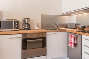 A modern kitchen with a microwave, coffee maker, toaster, and oven.