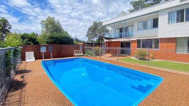 A rectangular swimming pool with a blue interior, surrounded by a brick wall and a metal fence. - Pirralea (Nelson Bay)