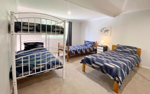 Een kamer met drie stapelbedden, een houten stoel, een klein nachtkastje met een lamp en een wereldkaart aan de muur.