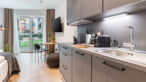 A modern kitchen with a large island, a built-in oven, and a stainless steel sink. - Limehome Münster Von-Steuben-Str. (Münster)