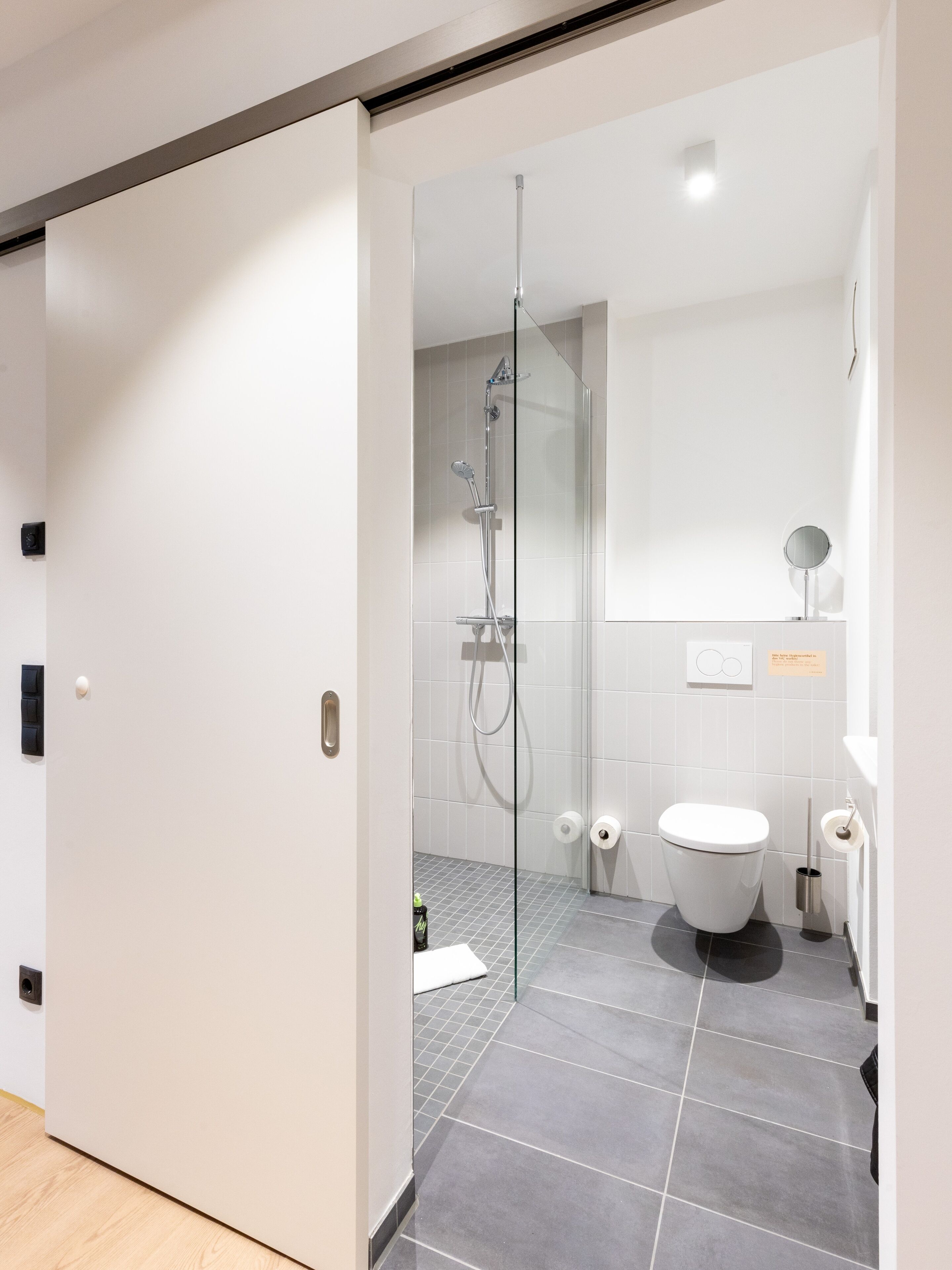 A modern bathroom with a glass shower enclosure, a toilet, and a sink.