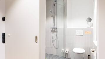 A modern bathroom with a glass shower enclosure, a toilet, and a sink.