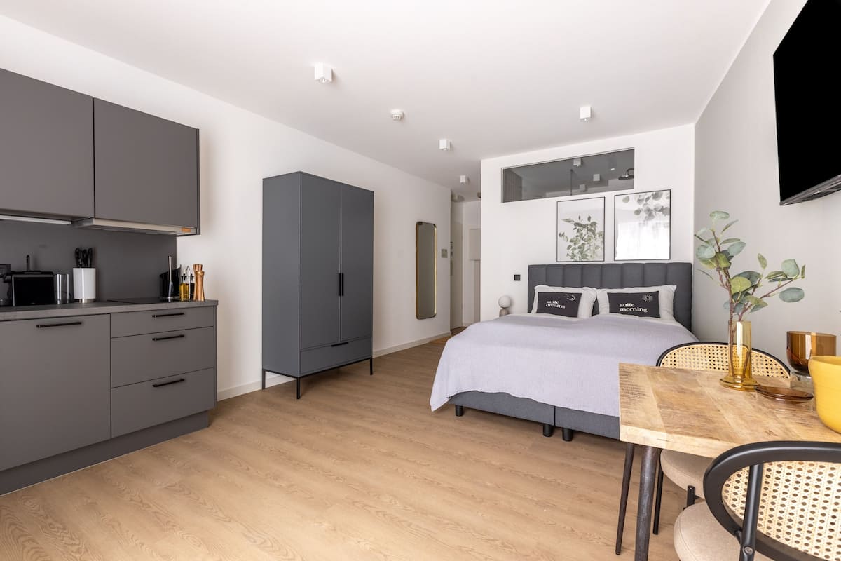 Quarto moderno com cama, mesa de cabeceira e guarda-roupa espaçoso.