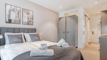 Ein modernes Schlafzimmer mit einem Bett, grauer Bettwäsche, zwei Kissen, einer grauen Strickdecke und einem grauen Kleiderschrank.