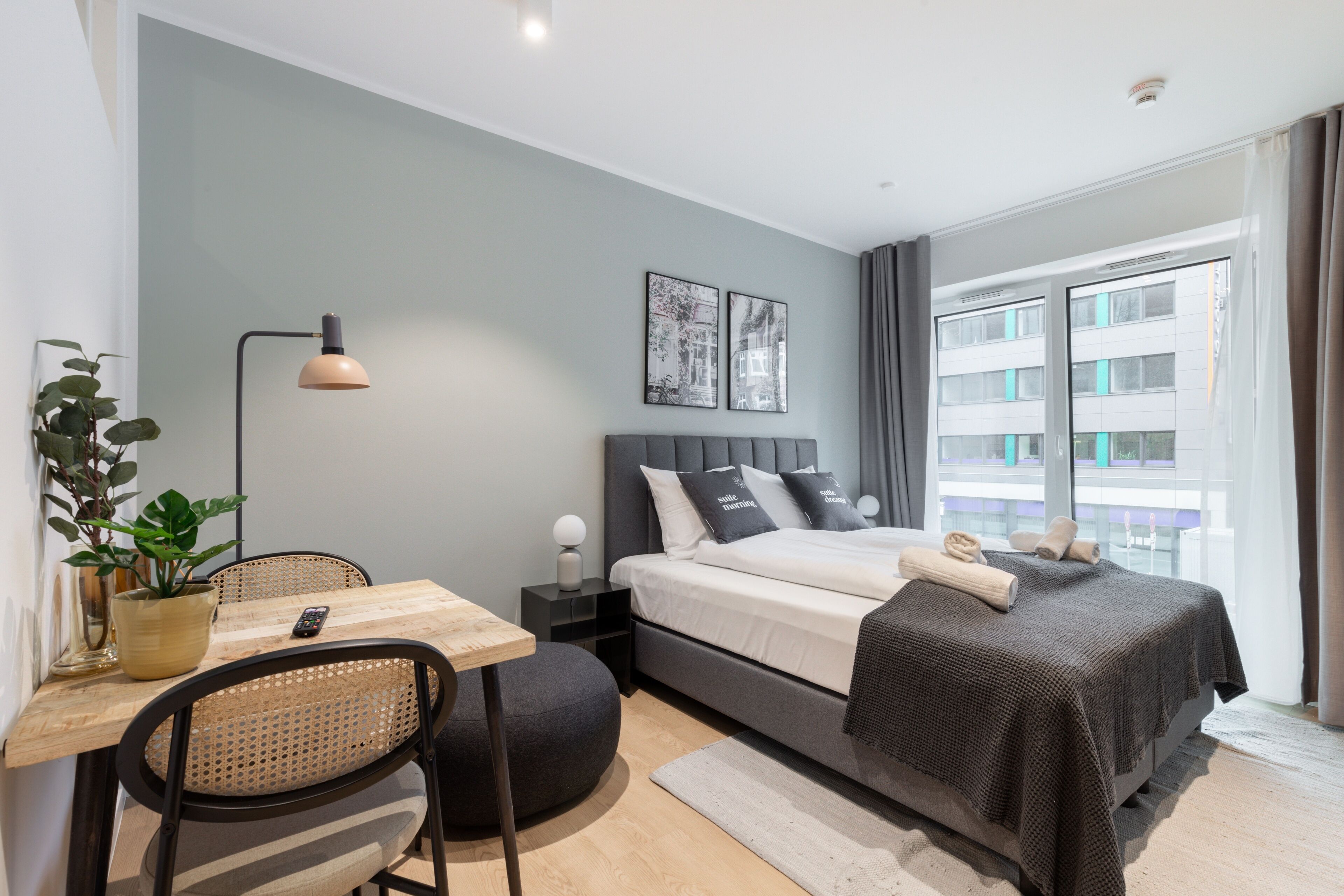 Una camera da letto moderna con un letto, comodino, lampada e vista sulla città.