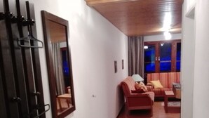 Une pièce avec un plancher en bois, un meuble noir sur lequel est posé un bol, un canapé rouge et un miroir au mur.