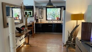 Eine moderne Küche mit Holzboden, einem großen Fenster und einem Essbereich mit Tisch und Stühlen.