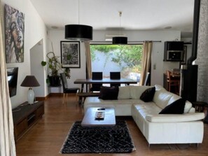 A modern living room with a white sofa, a coffee table, and a dining area with a table and chairs. - VILLA GRISEOR (Porto-Vecchio)