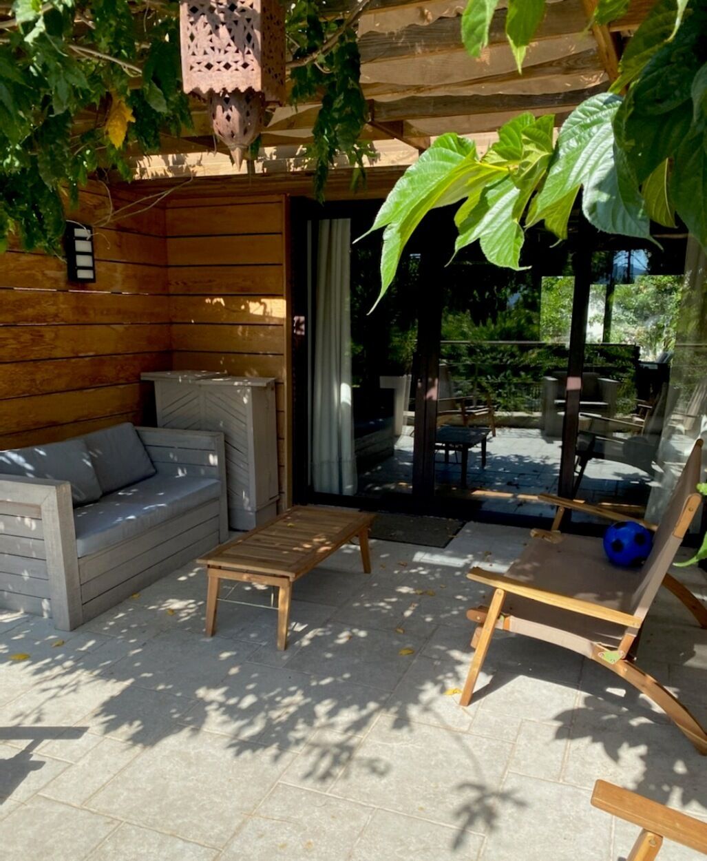 Eine Außenpatio-Terrasse mit einer hölzernen Bank, einer gepolsterten Sitzecke und einem Tisch.