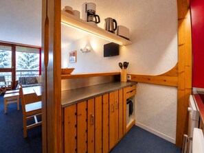 A compact kitchen with wooden cabinets, a countertop, and a built-in oven. - 2nd floor, view resort, balcony, tv, 40m², Les Arcs (Les Arcs)