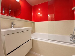 A bathroom with a white bathtub, a sink with a mirror above it, and a red wall. - 2nd floor, view resort, balcony, tv, 40m², Les Arcs (Les Arcs)