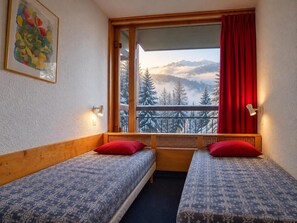 A room with two beds, a window with a view of snow-covered mountains, and a red curtain. - 2nd floor, view resort, balcony, tv, 40m², Les Arcs (Les Arcs)