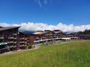A multi-story hotel with balconies, a covered outdoor area, and a view of mountains. - Ski-in/ski-out & foot of the slopes, 1st floor, view resort, tv, 33m², Les Arcs (Les Arcs)
