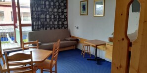 A small, cozy room with a sofa, a wooden table, and a chair. There is a window with a view of a building outside. - Ski-in/ski-out & foot of the slopes, 1st floor, view resort, tv, 33m², Les Arcs (Les Arcs)
