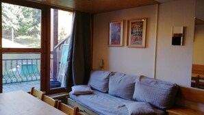 Een gezellige kamer met een bank, een eettafel en uitzicht op een terras.