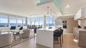 A modern kitchen with a central island, large windows, and a view of the sea. - Ocean Front with Rooftop Pool Access (Destin)