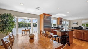 A spacious kitchen with a large island, wooden cabinets, and a view of a lake. - Private Deep Water Dock, heated pool and hot tub RPMS005 (Marstons Mills)