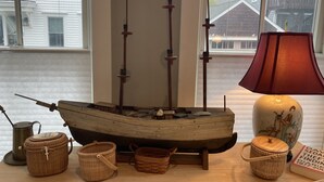 Une maquette de bateau est posée sur une table, à côté de paniers et d’une lampe.