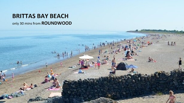 Brittatas Bay strand met een stenen muur en mensen die zonnebaden en zwemmen.