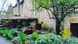 Un bâtiment en pierre doté d’un jardin où l’on peut admirer diverses plantes et rochers.