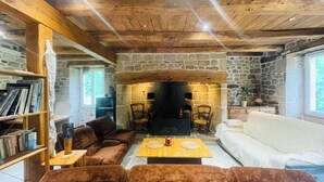 Un salon chaleureux avec une cheminée en pierre, un plafond en bois et une bibliothèque.