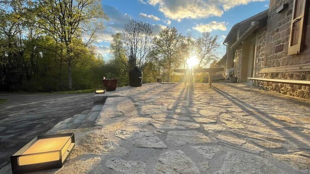 Un chemin de pierres mène à un bâtiment en pierre doté d’une porte en bois et d’une fenêtre.