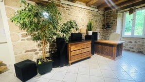 Une pièce avec un mur en pierre, un bureau en bois, une plante en pot et une fenêtre.