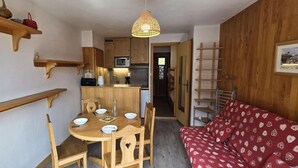 A compact living space with a dining area, kitchenette, and a red sofa with heart patterns. - 50m from ski slopes, 3rd floor, view village, balcony, tv, 23m², Champagny-en-Vanoise (Champagny-en-Vanoise)