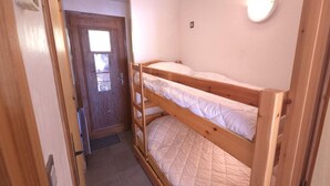 A narrow hallway leading to a room with two bunk beds, a wooden door, and a small window. - 50m from ski slopes, 3rd floor, view village, balcony, tv, 23m², Champagny-en-Vanoise (Champagny-en-Vanoise)