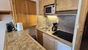 A compact kitchen with wooden cabinets, a microwave, a sink, a coffee maker, and a dishwasher. - 50m from ski slopes, 3rd floor, view village, balcony, tv, 23m², Champagny-en-Vanoise (Champagny-en-Vanoise)