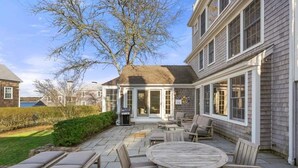 A patio with a round table and chairs, a grill, and a covered seating area.